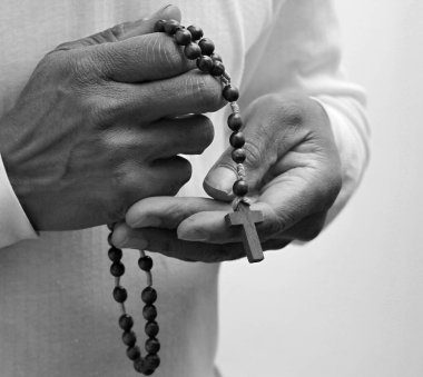 Kilisede dua eden bir adamın siyah beyaz fotoğrafı.