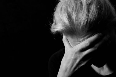 Depresyondan muzdarip bir kadın, elini koyu arka planda tutuyor.