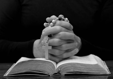 İnsanın orta kesimi haç ve İncil 'i tutarken dua eder.