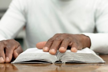 Afrika kökenli Amerikalı bir adam dua ederken elini açık İncil 'in üzerine koydu. 
