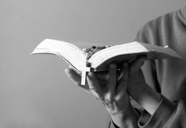 Kadın tespih ve incil ile dua ediyor.