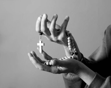 Genç bir kadın ellerinde tespihle dua ediyor. 