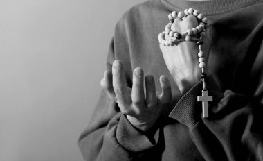 Genç bir kadın ellerinde tespihle dua ediyor. 