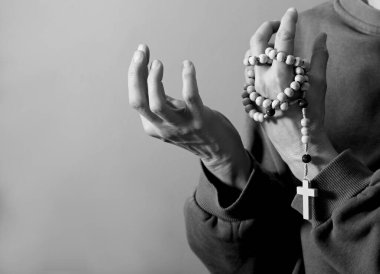 Genç bir kadın ellerinde tespihle dua ediyor. 