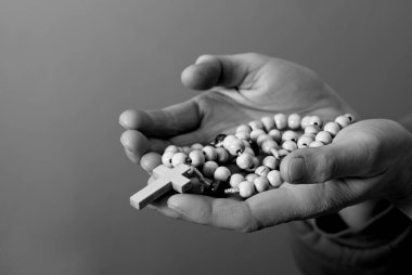 Genç bir kadın ellerinde tespihle dua ediyor. 