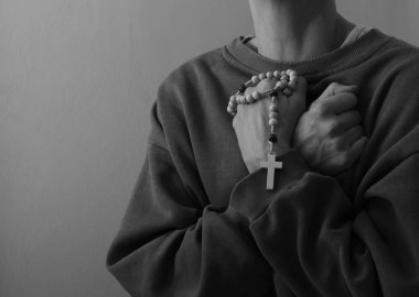 Genç bir kadın ellerinde tespihle dua ediyor. 