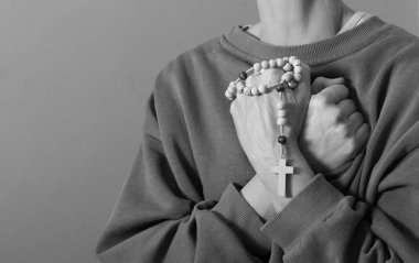 Genç bir kadın ellerinde tespihle dua ediyor. 