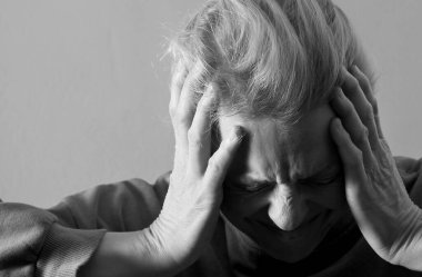 Depresyonda olan bir kadın, gri arka planda baş ağrısı