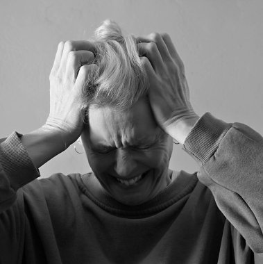 Depresyonda olan bir kadın, gri arka planda baş ağrısı