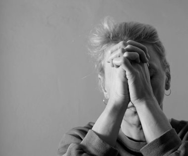 Genç bir kadın gri arka planda dua ediyor. 