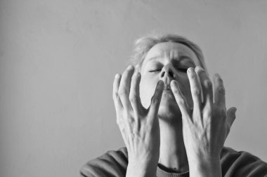 Genç bir kadın gri arka planda dua ediyor. 