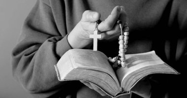 Kadın tespih ve incil ile dua ediyor.