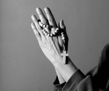 Genç bir kadın ellerinde tespihle dua ediyor. 