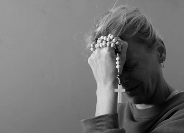 Genç bir kadın ellerinde tespihle dua ediyor. 