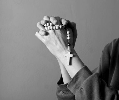 Genç bir kadın ellerinde tespihle dua ediyor. 