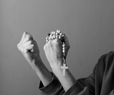 Genç bir kadın ellerinde tespihle dua ediyor. 