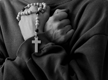 Genç bir kadın ellerinde tespihle dua ediyor. 