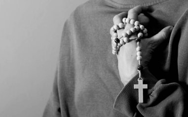 Genç bir kadın elinde tespihle dua ediyor. 