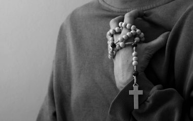 Genç bir kadın elinde tespihle dua ediyor. 