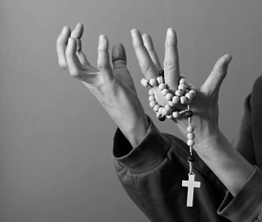 Genç bir kadın ellerinde tespihle dua ediyor. 