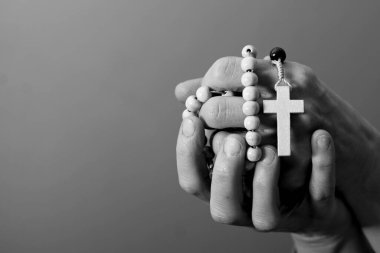 Genç bir kadın ellerinde tespihle dua ediyor. 