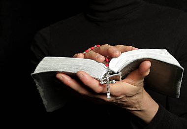 Kadın tespih ve incil ile dua ediyor.