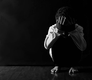 Genç yalnız Afrikalı Amerikalı çocuk siyah arka plana çömeldi. 