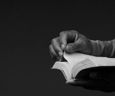 İncil 'le dua eden adam. Siyah arka planda dua eden adam