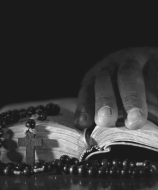 Elinde İncil 'le dua eden bir adam. Siyah arka planda dua eden adam
