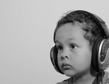 Kulaklıklı çocuk müziğin tadını çıkarıyor ve gri arka plana bakıyor. 