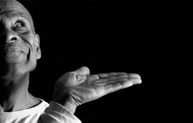 Üst düzey bir adamın portresi, siyah arka planda avuç içi olan bir şey gösteriyor.