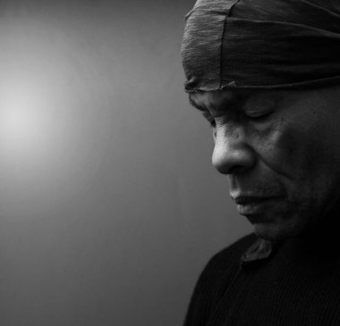 Gözleri kapalı Hristiyan bir adam stüdyoda karanlık arka plan için dua ediyor.