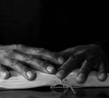 Papaz karanlık stüdyoda İncil okuyor, siyah beyaz fotoğraf. 