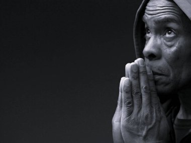 Dindar bir adam stüdyoda karanlık arka plan için dua ediyor.