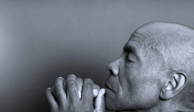 Gözleri kapalı bir Hıristiyan stüdyoda karanlık arka plan için dua ediyor. kopyalama alanı konsepti. siyah beyaz fotoğraf 