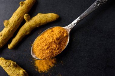 Kurumuş zerdeçal kökleri ve kaşıkta toz..