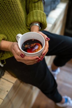 Kız elinde bir bardak sıcak şarap tutuyor..