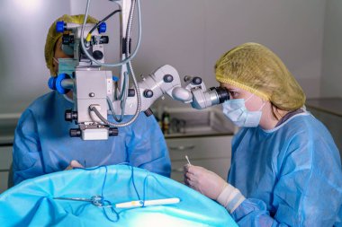 Blepharoplasty plastik cerrahi. Göz çevresindeki bölgenin yenilenmesi ve modifikasyonu. Estetik cerrah ve hemşireler bir kadın hastaya mikroskop kullanarak göz kapağı ameliyatı yapıyorlar.