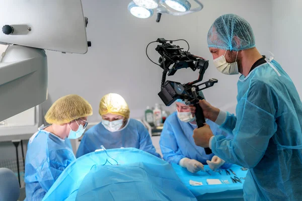 Blepharoplasty plastic surgery. A plastic surgeon and nurses perform eyelid surgery on a female patient. Male videographer makes a professional filming of the operation process