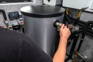 Modern elektrikli kazan dairesi. Otomatik kontrol üniteli su ısıtma sistemi için ekipman. Bir erkeğin elinin yakın çekimi.