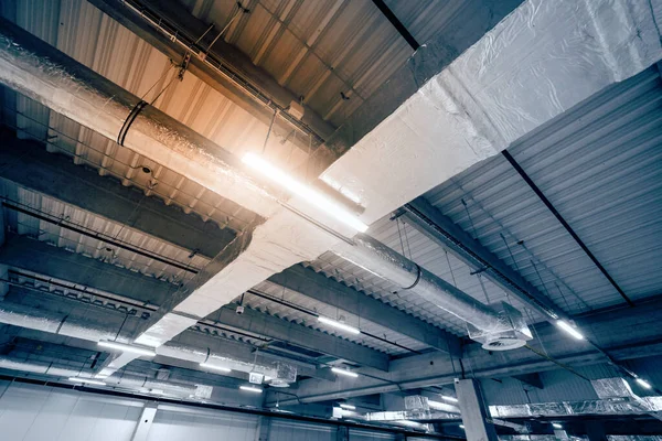 大仓库天花板上的通风系统 新大楼的天花板上挂着用银绝缘材料做的管子 — 图库照片