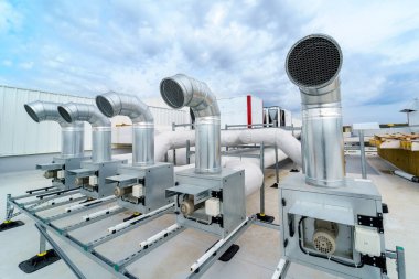 The air conditioning and ventilation system of a large industrial building is located on the roof. Large metal pipes for air duct, air conditioning, smoke removal and ventilation clipart