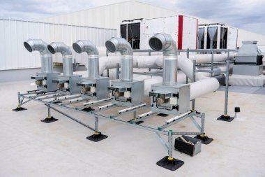 The air conditioning and ventilation system of a large industrial building is located on the roof. Large metal pipes for air duct, air conditioning, smoke removal and ventilation clipart