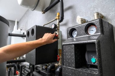 Modern elektrikli kazan dairesi. Otomatik kontrol üniteli su ısıtma sistemi için ekipman. Bir erkeğin elinin yakın çekimi.