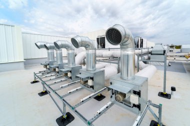 Büyük bir sanayi binasının havalandırma ve havalandırma sistemi çatıda yer almaktadır. Havalandırma, havalandırma, duman temizleme ve havalandırma için büyük metal borular.