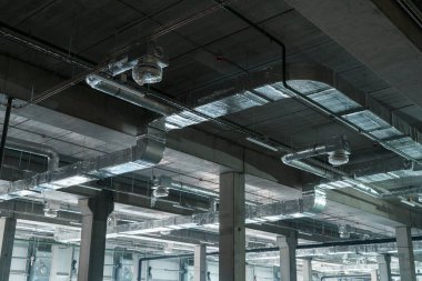 Tavanda büyük bir depoda havalandırma sistemi var. Yeni binanın tavanından sarkan gümüş yalıtımlı borular.