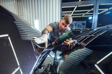 Teknisyen, arabanın dış tarafına dikkatlice vinil ambalaj uygulayarak, ilave koruma ve stil için pürüzsüz ve hassas bir son sağlıyor.