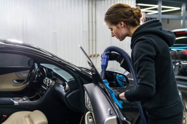 Organize garajda siyah arabayı dikkatlice temizleyen kadın.