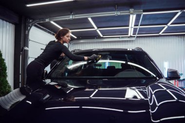 Two technicians collaborate to clean a car windshield, focusing on achieving a streak-free and spotless finish clipart