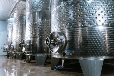Endüstriyel ölçekte şarap üretimi ve yaşlanma için kullanılan temiz ve modern bir şaraphanede geniş paslanmaz çelik fermantasyon tankları.